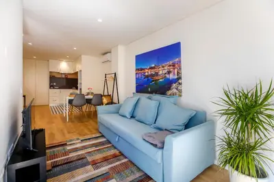 a living room with a blue couch and a kitchen at Oliveira Apartment`s in Porto