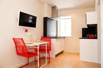 a kitchen with a table and four red chairs at Ribeira Cinema Apartments in Porto