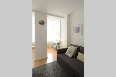 a living room with a black couch and a window at Softly Porto in Porto