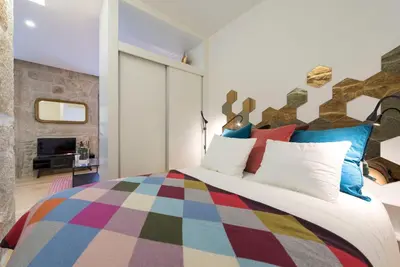 a bedroom with a large bed with colorful pillows at LovelyStay - Vitoria Viewpoint 1BR Flat in Porto