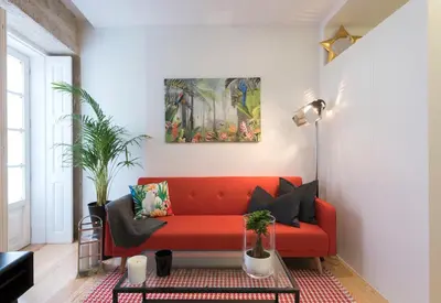a red couch in a living room with a painting on the wall at LovelyStay - Vitoria Viewpoint 1BR Flat in Porto