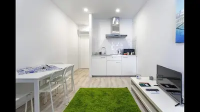 a white kitchen with a table and a green rug at City Heart Place 2 in Porto