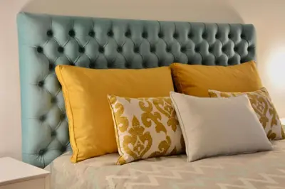 a bed with yellow pillows and a blue headboard at OHH - Caldeireiros Luxury Apartments in Porto