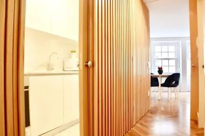 a kitchen with white cabinets and a table with a chair at OHH - Caldeireiros Luxury Apartments in Porto