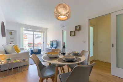 a living room with a table and chairs and a couch at Trindade Family Apartment w/ Parking Place in Porto