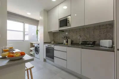 a kitchen with white cabinets and a bowl of fruit on a counter at Trindade Family Apartment w/ Parking Place in Porto