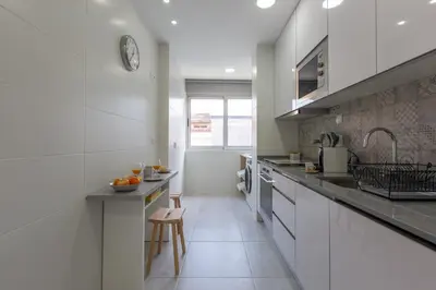 a white kitchen with a sink and a counter at Trindade Family Apartment w/ Parking Place in Porto