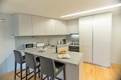 a kitchen with white cabinets and a kitchen island with chairs at Premium Style Apt by Porto City Hosts in Porto