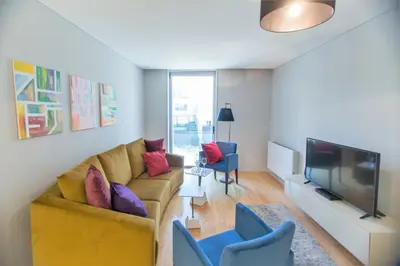 a living room with a yellow couch and blue chairs at Premium Style Apt by Porto City Hosts in Porto