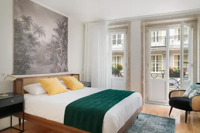 a bedroom with a large bed and two windows at FLORES PLAZA APARTMENT in Porto