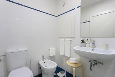 a white bathroom with a sink and a toilet at FLORES PLAZA APARTMENT in Porto
