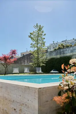 a swimming pool with two chairs and a tree at Oporto Maison Anselmo in Porto