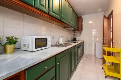 a kitchen with green cabinets and a sink at Renovated Feb25 Clerigos Cozy Balcony with self check in in Porto