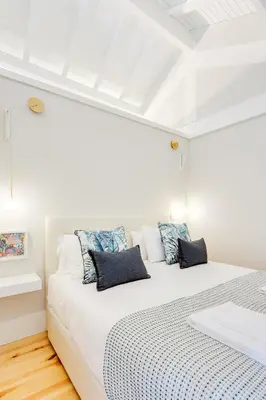 a white bedroom with a large bed with blue pillows at DA'HOME - Rola Art Work Studio in Porto