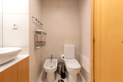 a white bathroom with a toilet and a sink at Sunny Loft in Downtown Porto with Private Parking in Porto