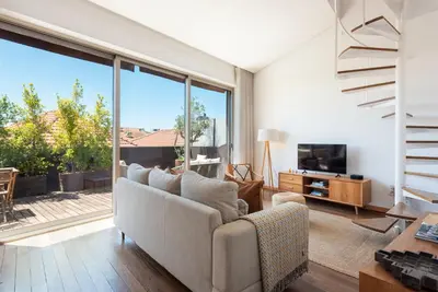 a living room with a couch and a large window at Sunny Loft in Downtown Porto with Private Parking in Porto