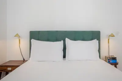 a bed with white pillows and a green headboard at Decompress at a Tranquil, Minimal Urban Oasis with an Edge in Porto