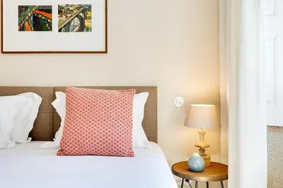 a bedroom with a bed with a red pillow and a table at Jardins da Muralha Apartments by DA'HOME in Porto