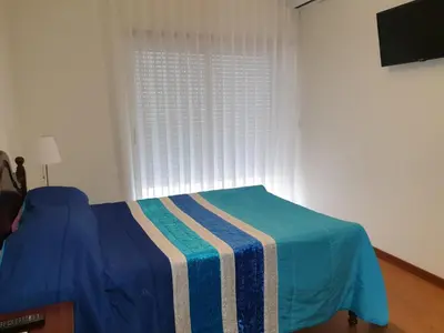 a bedroom with a bed with a blue blanket and a window at Alegria Downtown Apartments in Porto