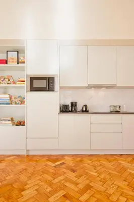 a kitchen with white cabinets and a wooden floor at Ribeira - Dixos Oporto Apartments IV in Porto