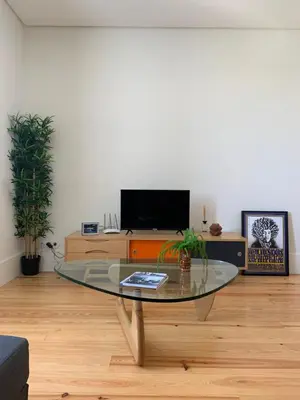 a living room with a glass table and a tv at Guest House Arca de Água in Porto