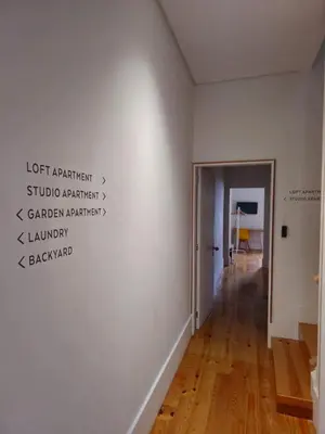 a hallway with a white wall with words on it at Guest House Arca de Água in Porto