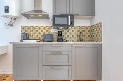 a kitchen with white cabinets and a tv on the wall at OPORTO GUEST Casa dos Clérigos in Porto