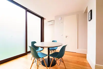 a table and chairs in a room with a large window at Morar Apartments Porto in Porto