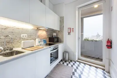 a white kitchen with a sink and a window at Alegria 283 in Porto