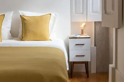 a bedroom with a bed and a nightstand with a yellow pillow at Alegria 283 in Porto
