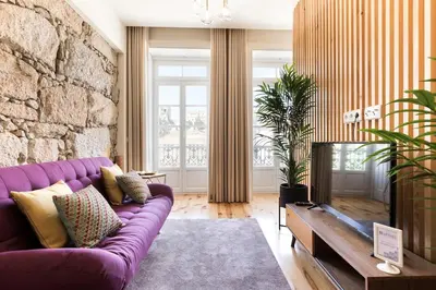a living room with a purple couch and a stone wall at Wine Luxury House in Porto