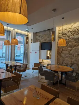 a restaurant with tables and chairs and a stone wall at Oportoflag center in Porto
