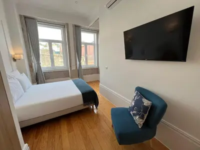 a bedroom with a bed and a chair and a flat screen tv at Oportoflag center in Porto