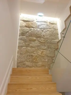a stone wall with wooden stairs in a room at Oportoflag center in Porto