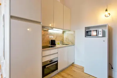 a kitchen with white cabinets and a refrigerator at APOSENTUS - Clerigos Tower view Mezzanine in Porto