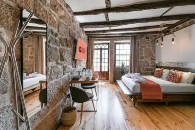 a room with a stone wall with a table and chairs at GuestReady - CastleRock Pub & Hotel in Porto