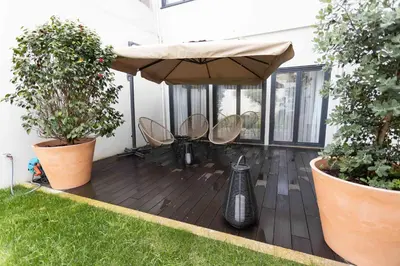 a patio with chairs and an umbrella and some plants at Stayin Apartments - Rua do Sol in Porto