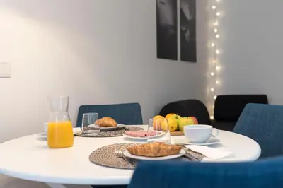 a white table with breakfast foods and orange juice at Heart of D Pedro Apartments in Porto
