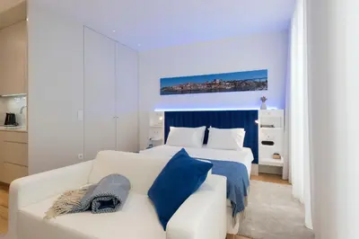 a bedroom with two beds and a white couch at Heart of D Pedro Apartments in Porto