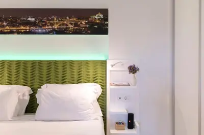 a bed with white pillows and a picture above it at Heart of D. Pedro Apartments III in Porto