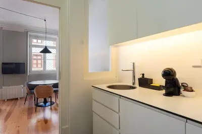 a white kitchen with a sink and a table at Cedofeita Premium Apartment 1F in Porto