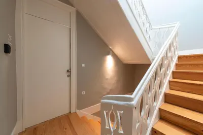 a white staircase with a blue chair next to a door at Cedofeita Premium Apartment 2B in Porto
