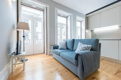 a blue couch in a living room with windows at LovelyStay - Porto Windows with AC by central station in Porto
