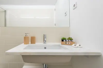 a white bathroom with a sink and a mirror at LovelyStay - Porto Windows with AC by central station in Porto