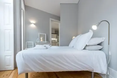 a white bedroom with a large white bed with white pillows at LovelyStay - Porto Windows with AC by central station in Porto
