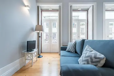 a living room with a blue couch and a television at LovelyStay - Porto Windows with AC by central station in Porto