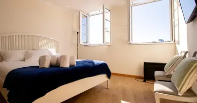 a bedroom with a bed and two windows at Casa do Recanto in Porto