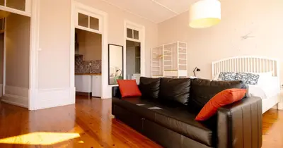 a living room with a black couch and red pillows at Casa do Recanto in Porto