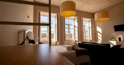 a living room with a table and some windows at Casa do Recanto in Porto