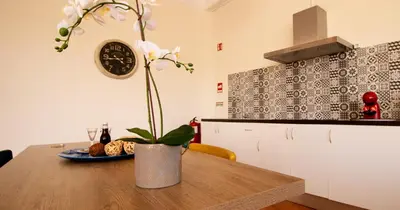 a kitchen with a wooden table with a vase with flowers at Casa do Recanto - Loft vista rio in Porto